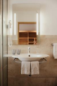 a bathroom with a sink and a mirror and towels at Rifugio Alpino Pralongià in Corvara in Badia