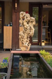 a rock pillar next to a pond in front of a house at Xianqingshan Homestay in Hangzhou