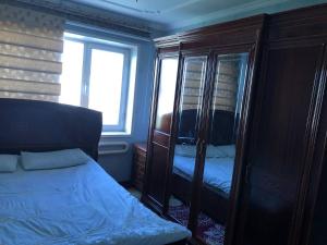 a bedroom with a bed and a cabinet with a window at Korzinka in Fergana