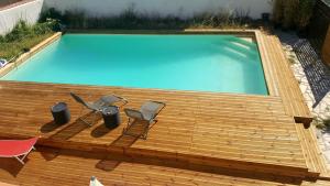 a swimming pool on a wooden deck with two chairs at STUDIO DU CHARME PROVENCAL in Sénas