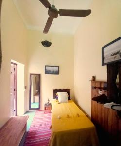 um quarto com uma cama amarela e uma ventoinha de tecto em Riad Alqimam em Marrakech