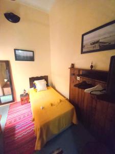 um quarto com uma cama amarela e uma televisão em Riad Alqimam em Marrakech