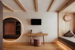 Habitación con mesa y TV en la pared. en Rifugio Alpino Pralongià en Corvara in Badia