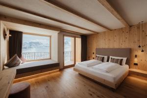 - une chambre avec un grand lit et une grande fenêtre dans l'établissement Rifugio Alpino Pralongià, à Corvara in Badia