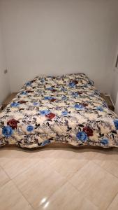 a bed with a floral comforter on the floor at Appartement Taza in Taza