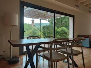 une table à manger avec des chaises et une grande fenêtre dans l'établissement Designer home with pool near beach and village, à Alella