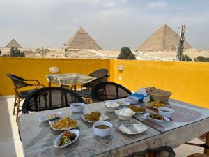 una mesa con comida en ella con las pirámides en el fondo en Pyramids Plateau View en El Cairo