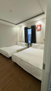 2 Betten in einem Hotelzimmer mit Fenster in der Unterkunft AT Hotel Cần Thơ in Ấp An Mỹ