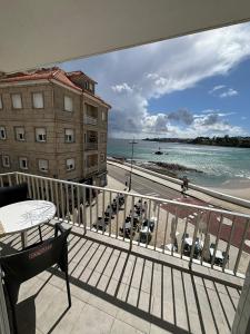 uma varanda com vista para a praia e para o oceano em Alojamientos Plaza Portugal em Sanxenxo