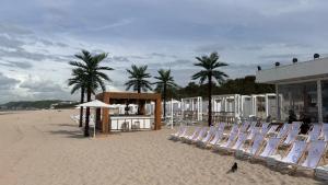 a beach with chairs and a building and palm trees at Crest View 777th - Apartament & SPA in Międzyzdroje