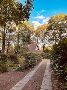 una pasarela en un patio con árboles y una casa en Fijn vakantiehuis op de golfbaan met eigen sauna!, en Winterswijk Henxel