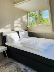 Una cama con sábanas blancas y una ventana en una habitación en Fijn vakantiehuis op de golfbaan met eigen sauna!, en Winterswijk Henxel