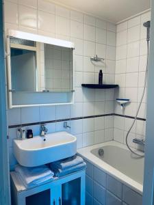 y baño con lavabo, espejo y bañera. en Fijn vakantiehuis op de golfbaan met eigen sauna!, en Winterswijk Henxel