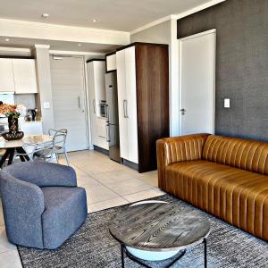 sala de estar con sofá de cuero marrón y mesa en Luxury Masingita towers 9th floor apartment, en Johannesburgo
