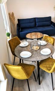 赫爾的住宿－White Shell Apartament Hel，一张桌子,上面摆放着四把黄色椅子和一张蓝色的沙发