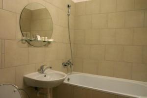 a bathroom with a tub, sink and mirror at Hotel Jelen in Hlohovec