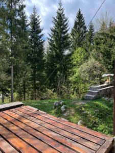 une terrasse en bois avec des arbres en arrière-plan dans l'établissement ~Chalet_Rifugio tra i boschi~, à Sella Nevea