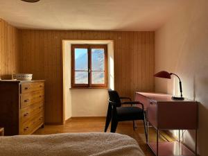 Mesocco的住宿－Waterfall House - retreat, swim, bike, hike and ski，一间卧室配有桌子、椅子和窗户