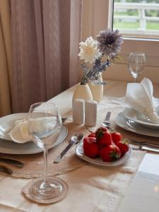 a table with a plate of strawberries and a vase with flowers at Stylish studio apartment with terrace in Ingolstadt