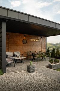 eine Terrasse mit Tischen, Stühlen und einer Uhr in der Unterkunft Woodhouse in Bijelo Polje