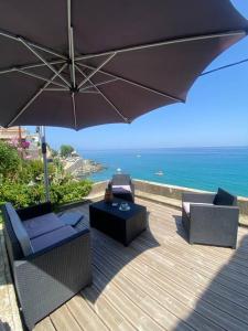 a patio with chairs and an umbrella and the ocean at Maison en bord de mer en Corse Lavasina Brando in Brando