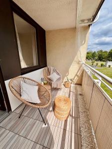 balcón con silla de mimbre y taburete en Stylish studio apartment with terrace, en Ingolstadt
