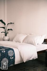 a bed with white sheets and a potted plant at This is it Beachfront - Rooms, Cafe & Events in Arambol