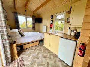 a small kitchen with a bed and a sink in a tiny house at Shepherds Retreat Anglesey in Llanerchymedd