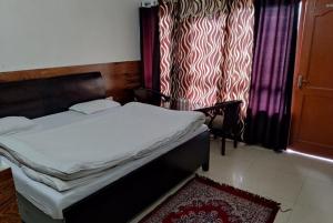 een slaapkamer met een bed en een raam met gordijnen bij Goroomgo Rohila Lodge Nainital Near Naini Lake - Luxury Room Mountain View in Nainital
