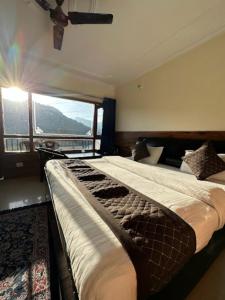 een slaapkamer met 2 bedden en een groot raam bij Goroomgo Rohila Lodge Nainital Near Naini Lake - Luxury Room Mountain View in Nainital