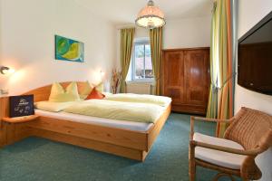 a bedroom with a large bed and a chair at Pension Pilsachhof in Arriach +25 photos