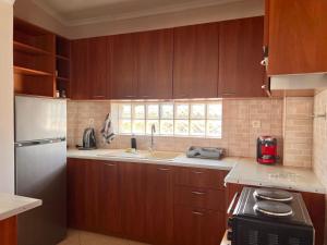 a kitchen with wooden cabinets and a sink and a refrigerator at Villa Verano in Asprovalta