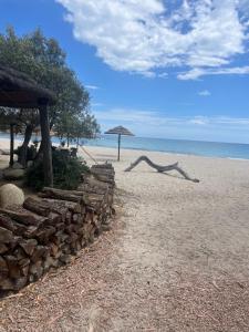 een stapel houtblokken op een strand met een parasol bij Favone Mini Villa Playa del Oro in Favone
