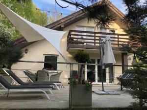 a patio with chairs and an umbrella in front of a house at Mazurska Riwiera in Dabrowa +28 photos
