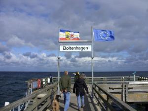 a man and woman walking on a pier with flags at Ferienhaus Mandy in Wohlenberg