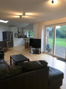 sala de estar con sofá, mesa y cocina en Fully accessible Hampshire Home en Waterlooville