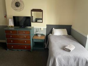a bedroom with a bed and a dresser with a mirror at The Olde Swan Hotel in Chertsey