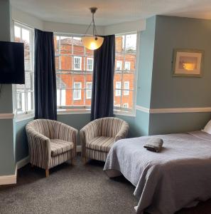 a bedroom with two chairs and a bed and a window at The Olde Swan Hotel in Chertsey