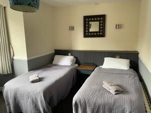 two beds in a hotel room with towels on them at The Olde Swan Hotel in Chertsey