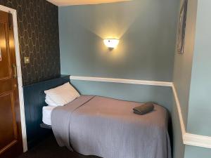 a small room with a bed and a light on the wall at The Olde Swan Hotel in Chertsey