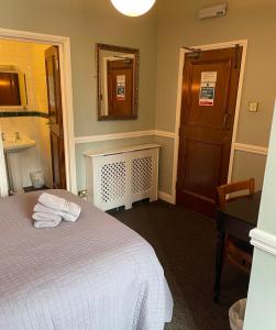 a bedroom with a bed and a sink and a mirror at The Olde Swan Hotel in Chertsey