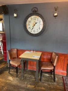 a table and chairs with a clock on the wall at The Olde Swan Hotel in Chertsey