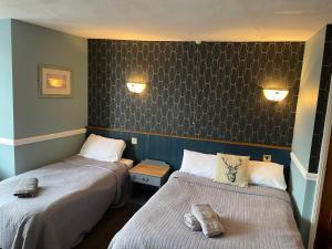 a room with two beds and a wall with two lights at The Olde Swan Hotel in Chertsey
