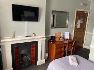 a room with a fireplace and a television on the wall at The Olde Swan Hotel in Chertsey