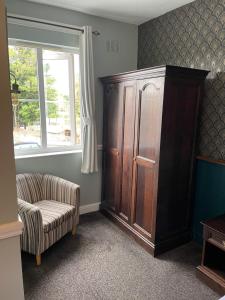 a living room with a large wooden cabinet and a chair at The Olde Swan Hotel in Chertsey