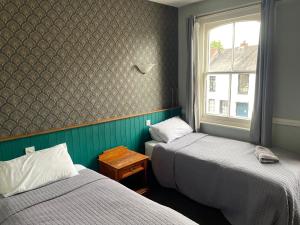 two twin beds in a room with a window at The Olde Swan Hotel in Chertsey