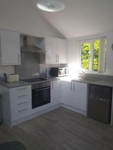 a kitchen with white cabinets and a stove top oven at Lanarth Chalet in Hayle Cornwall in Hayle