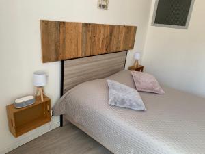 1 cama con cabecero de madera y 2 almohadas en La Tomette en Maury