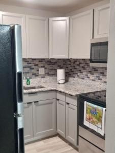 a kitchen with white cabinets and a black refrigerator at Seeing Busch Gardens from two apartments in Tampa