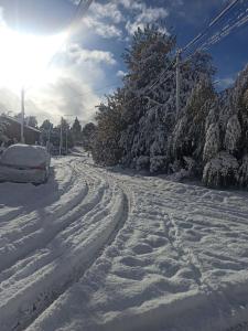 a road covered in snow with a car driving down it at Alma de Maitén in San Carlos de Bariloche
